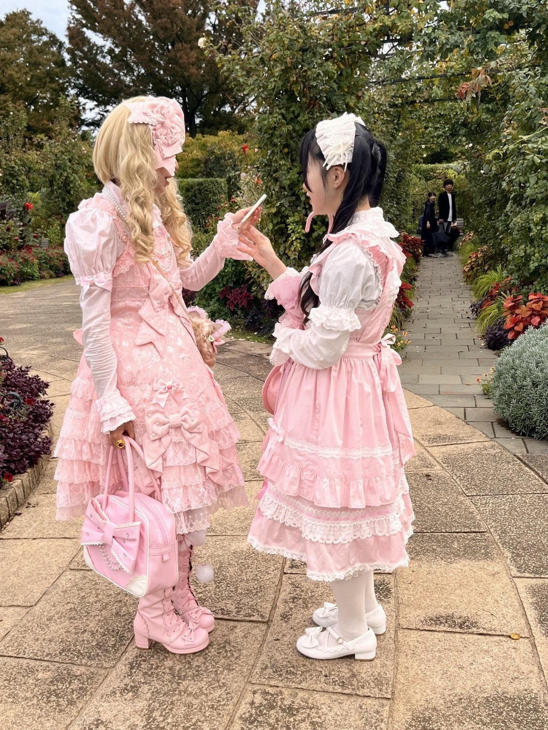 Two Lolita fashion guests talking together in a garden.